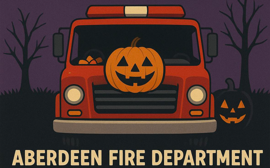 A fire truck with jack-o’-lanterns on its grill and beside it. Trees without leaves are in the background. Text below reads “Aberdeen Fire Department.”.
